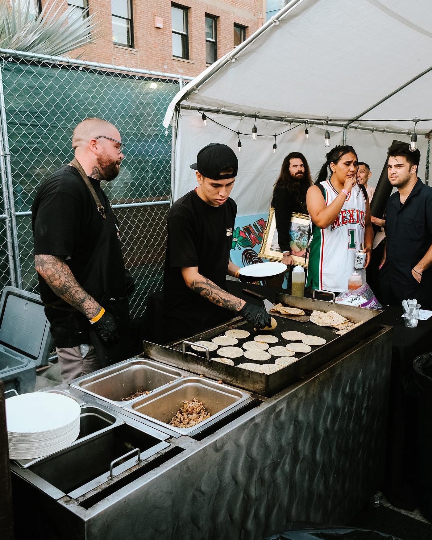 El equipo de Tacos El Gringo sirviendo tacos en un evento de noche
