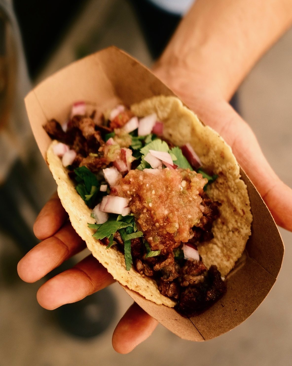 A Tacos El Gringo taco held up in a paper boat