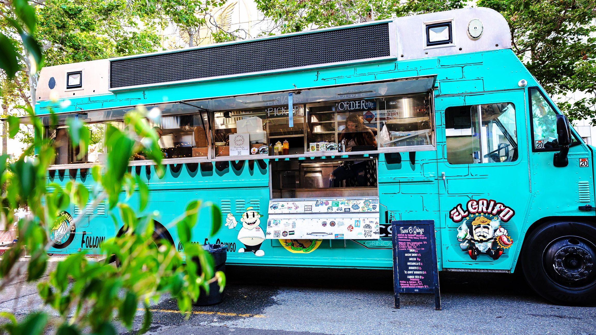 El food truck turquesa de Tacos El Gringo estacionado bajo los árboles en Santa Ana