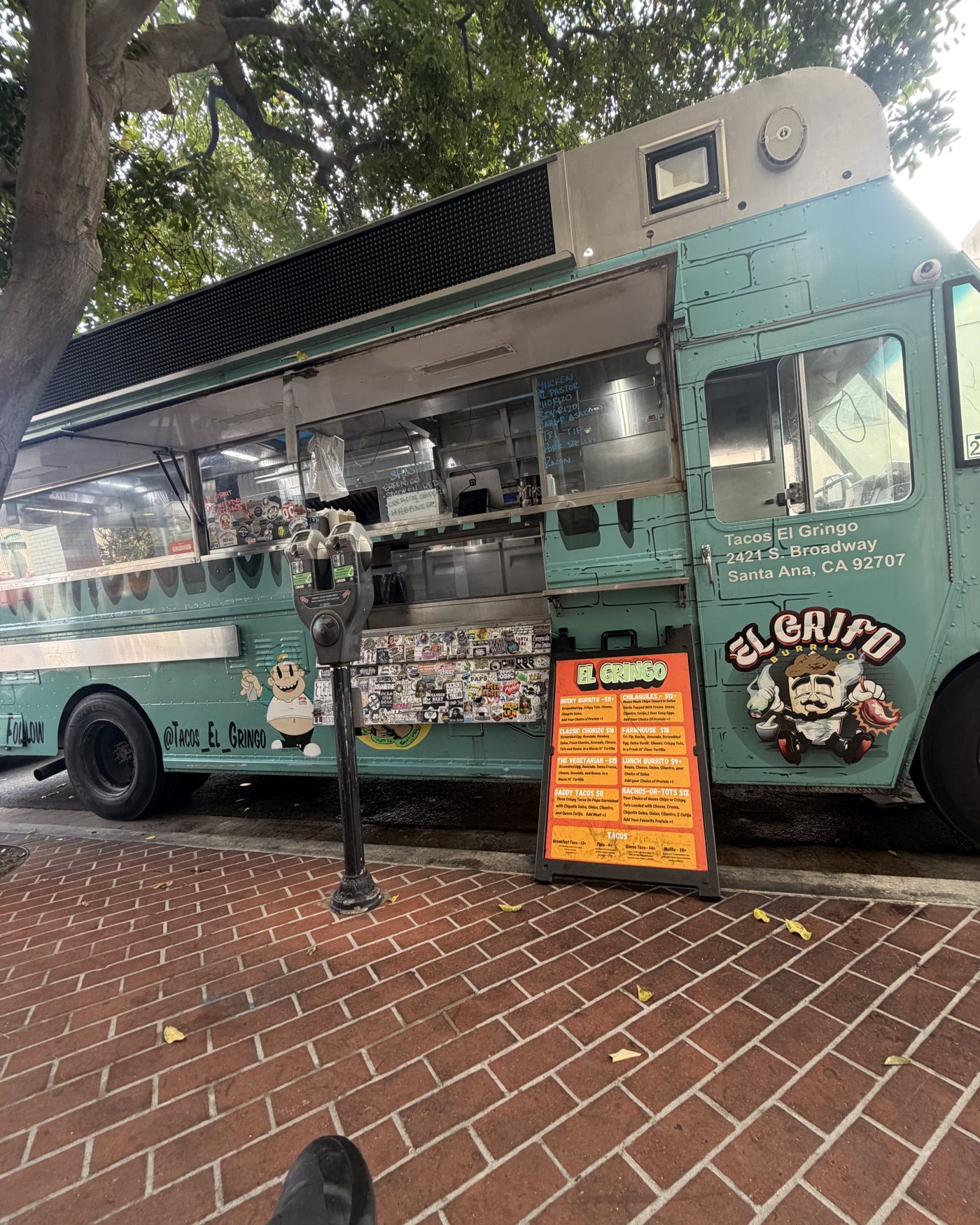 El truck de Tacos El Gringo estacionado en una banqueta de ladrillo en Santa Ana